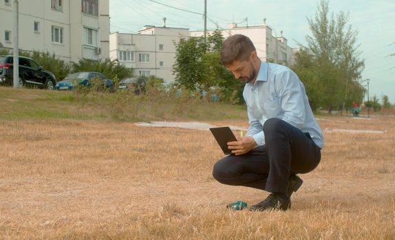 Incorrectly planted lawn. The grass dried up. Ecological inspector writing in a diary. Check of planting in the city park