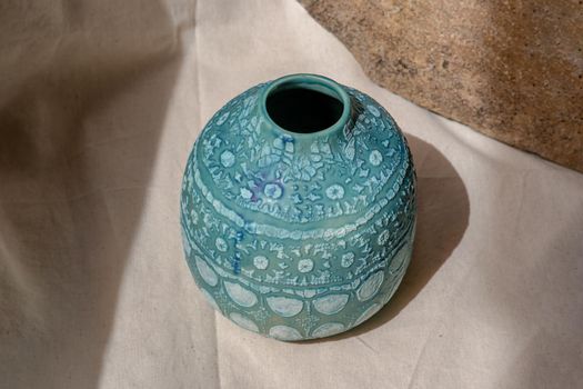 Blue handmade ceramic vase on white textured table cloth. Home decor, Copy space, Selective focus.
