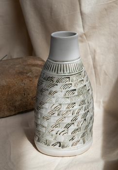 White and Black Handmade ceramic vase on white textured table cloth. Home decor, Copy space, Selective focus.