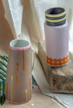 Two Brown and Pink handmade ceramic vases on white textured table cloth. Home decor, Copy space, Selective focus.