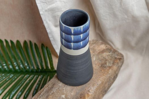 Blue handmade ceramic vase on white textured table cloth. Home decor, Copy space, Selective focus.