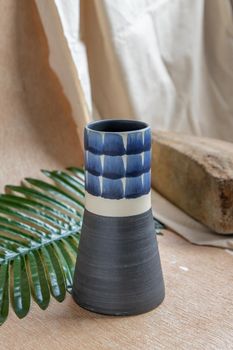 Blue handmade ceramic vase on white textured table cloth. Home decor, Copy space, Selective focus.
