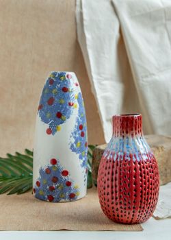 Two Blue and Red handmade ceramic vases on white textured table cloth. Home decor, Copy space, Selective focus.
