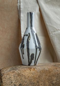 Black and White handmade ceramic vase on white textured table cloth. Home decor, Copy space, Selective focus.