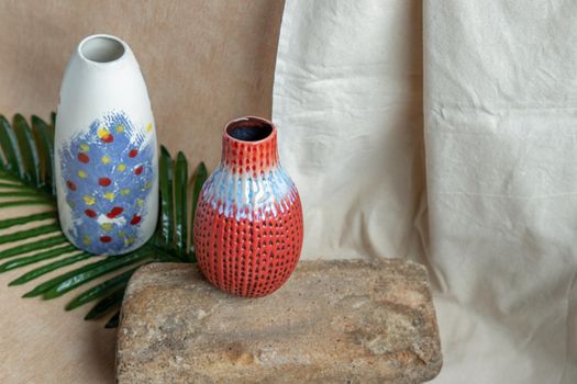 Two Blue and Red handmade ceramic vases on white textured table cloth. Home decor, Copy space, Selective focus.