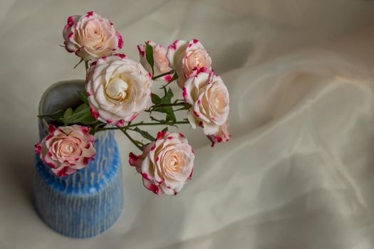 Bouquet of flower in Blue handmade ceramic vase on Blush textured table cloth. Home decor, Copy space, Selective focus.
