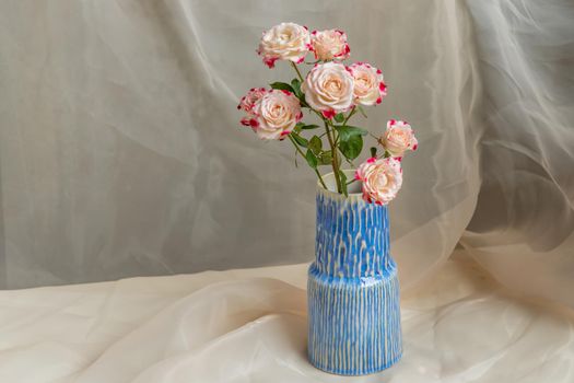 Bouquet of flower in Blue handmade ceramic vase on Blush textured table cloth. Home decor, Copy space, Selective focus.