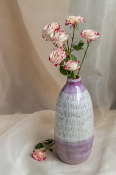 Bouquet of flower in Purple and White handmade ceramic vase on Blush textured table cloth. Home decor, Copy space, Selective focus.