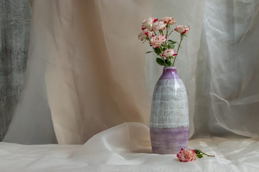 Bouquet of flower in Purple and White handmade ceramic vase on Blush textured table cloth. Home decor, Copy space, Selective focus.
