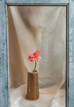 Pink flower in Brown handmade ceramic vase on Blush textured table cloth. Home decor, Copy space, Selective focus.