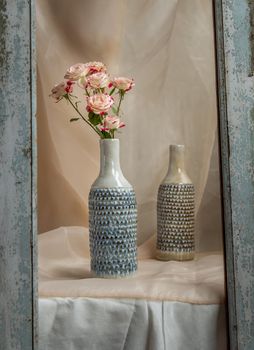 Bouquet of Pink flowers in Blue handmade ceramic vases in Wooden frame on Blush textured table cloth. Home decor, Copy space, Selective focus.