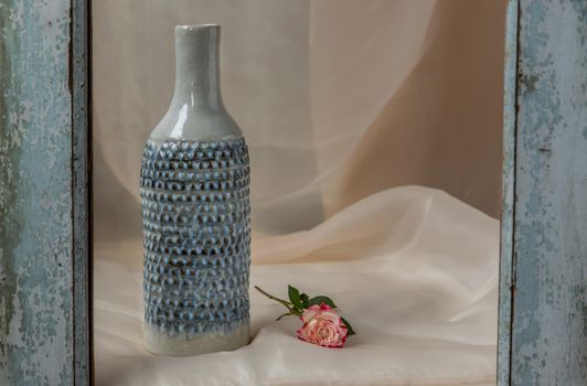 Blue handmade ceramic vase with flower on Blush textured table cloth.  Home decor, Copy space, Selective focus.