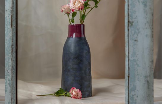 Bouquet of flower in Blue handmade ceramic vase on Blush textured table cloth. Home decor, Copy space, Selective focus.