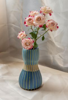 Bouquet of flower in Blue handmade ceramic vase on Blush textured table cloth. Home decor, Copy space, Selective focus.
