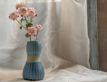 Bouquet of flower in Blue handmade ceramic vase on Blush textured table cloth. Home decor, Copy space, Selective focus.