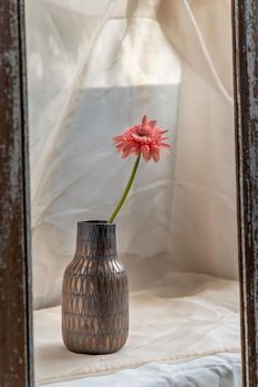 Pink flower in Copper color handmade ceramic vase and on Blush textured table cloth. Home decor, Copy space, Selective focus.
