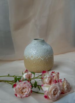 White and Yellow handmade ceramic vase with Bouquet of flower on Blush textured table cloth. Home decor, Copy space, Selective focus.