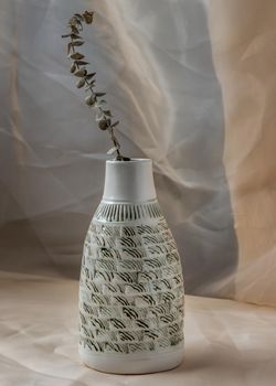 Dried flowers in White ceramic vase bottle shape on Blush textured table cloth. Home decor, Copy space, Selective focus.