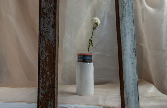 White flower in White handmade ceramic vase and on Blush textured table cloth. Home decor, Copy space, Selective focus.