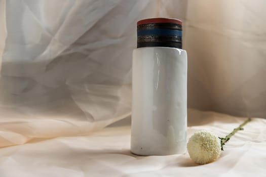 White handmade ceramic vase with White flower on Blush textured table cloth. Home decor, Copy space, Selective focus.