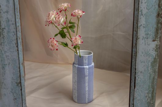 Bouquet of flowers in Blue handmade ceramic vase on Blush textured table cloth. Home decor, Copy space, Selective focus.