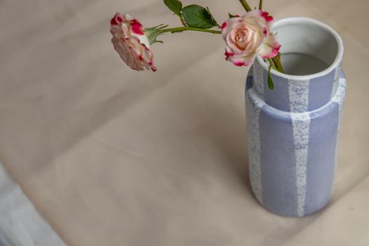 Bouquet of flowers in Blue handmade ceramic vase on Blush textured table cloth. Home decor, Copy space, Selective focus.