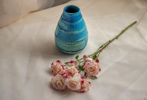 Blue handmade ceramic vase with Bouquet of Pink flowers on Blush textured table cloth. Home decor, Copy space, Selective focus.