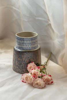 Blue handmade ceramic vase with Bouquet of flowers on Blush textured table cloth. Home decor, Copy space, Selective focus.