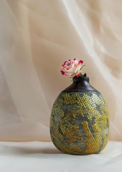 Flower in Yellow handmade ceramic vase on Blush textured table cloth. Home decor, Copy space, Selective focus.