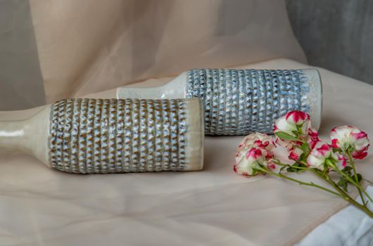 Two handmade ceramic vase bottle shape with Bouquet of flowers on Blush textured table cloth. Home decor, Copy space, Selective focus.
