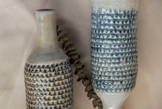 Close-up of Two handmade ceramic vase bottle shape on Blush textured table cloth. Home decor, Copy space, Selective focus.