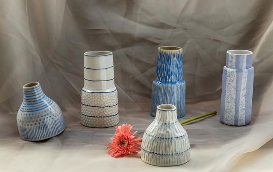 Five Blue and White handmade ceramic vase with Pink flower on Blush textured table cloth. Home decor, Copy space, Selective focus.