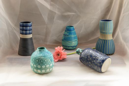 Five Blue handmade ceramic vase with Pink flower on Blush textured table cloth. Home decor, Copy space, Selective focus.
