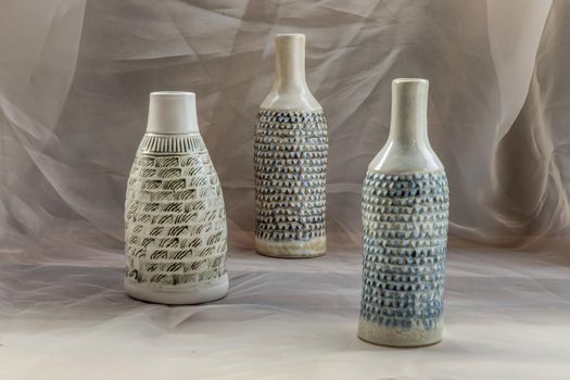 Three handmade ceramic vase bottle shape on Blush textured table cloth. Home decor, Copy space, Selective focus.
