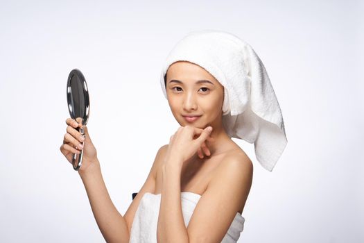 pretty asian woman in the mirror in trousers towel on head rejuvenation clear skin. High quality photo