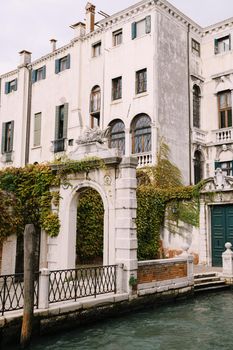 Beautiful stone arched entrance to the building, green door and classic Venetian windows. Details of the facades of buildings on the streets of Venice, Italy.