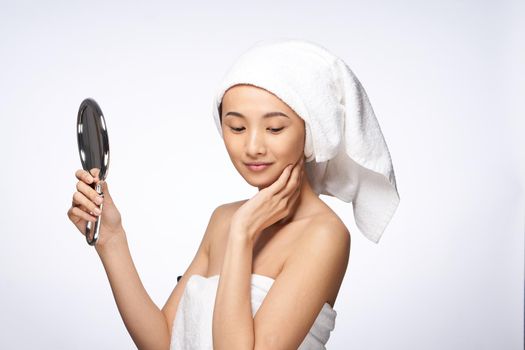 pretty asian woman in the mirror in trousers towel on head rejuvenation clear skin. High quality photo
