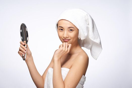 pretty asian woman in the mirror in trousers towel on head rejuvenation clear skin. High quality photo