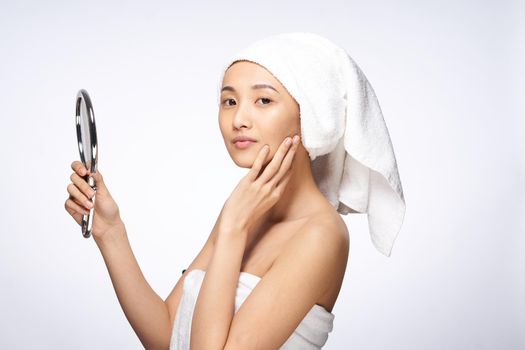 pretty asian woman in the mirror in trousers towel on head rejuvenation clear skin. High quality photo