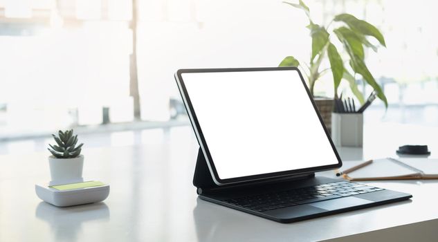 Cropped shot of workplace with tablet blank screen and office supplies in simple workspace