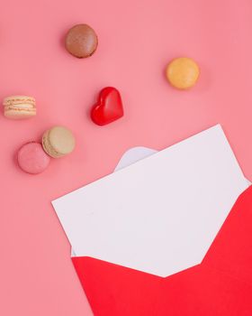 open envelope with empty blank, heart and macaroons on pink background