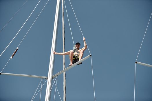 Croatia, Split, 15 September 2019: The sailor costs on the top part of a mast, participant of a sailing regatta with blue sky on a background, people prepare for the forthcoming race