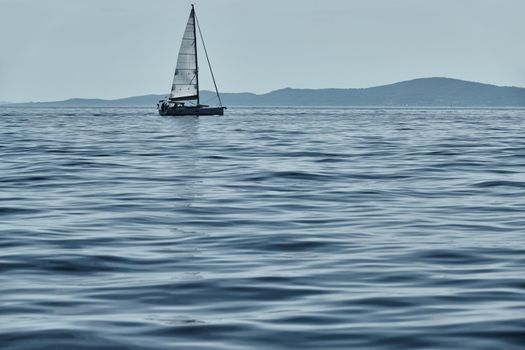 Beautiful sea landscape with lonely boat on the horizon, island is on background, colorful