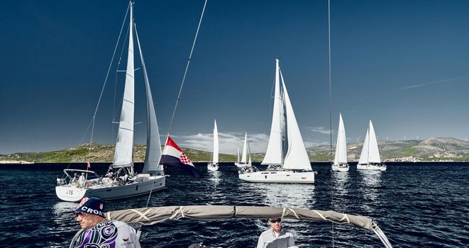 Sailboats compete in a sail regatta, the team turns off the boat, reflection of sails on water, multicolored spinnakers, number of boat is on aft boats, Croatia, Mediterranean Sea, 18 September 2019