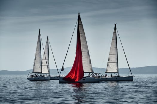 The race of sailboats, a regatta, reflection of sails on water, Intense competition, number of boat is on aft boats, island with windmills are on background