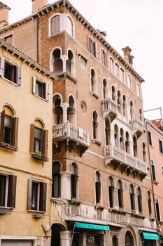 A five-storey stone building with white balconies with columns, classic Venetian arched windows.