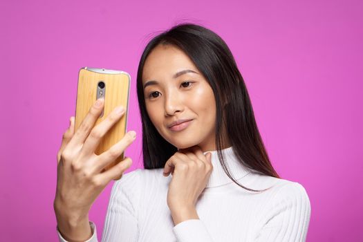 cute brunette phone in hand internet technology lifestyle pink background. High quality photo