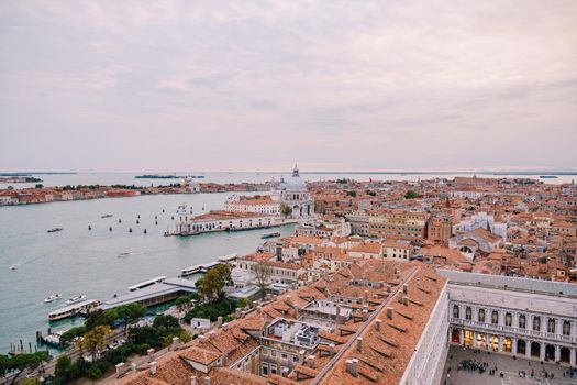 Aerial view from huge cathedral bell tower St Mark's Campanile on Santa Maria - Della - Salute, sunset sky and orange roof. Venice, Italy