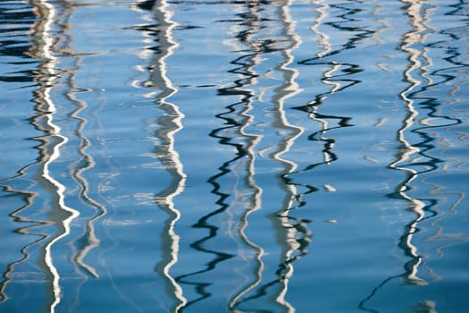 Reflection of masts of sailboats on water, interesting texture, smooth lines of water, a sail regatta, reflection of masts on water, ropes and aluminum