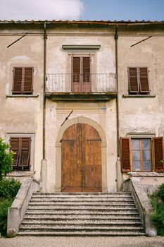 The facade of an old villa in Italy, in Florence. Stone staircase, wooden door, windows with wooden shutters.